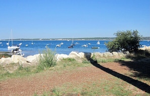 A coastal area with boats on the water, a rocky shoreline, and a clear sky.