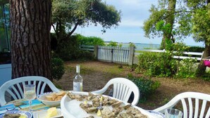 Een gedekte tafel met oesters op ijs, een fles witte wijn en uitzicht op zee.