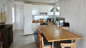 Een moderne keuken met witte kasten, een houten eettafel en een hangende lamp.
