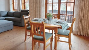 A dining area with a wooden table, chairs, and a potted plant.