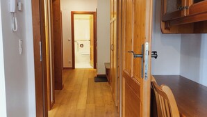A hallway with wooden flooring and doors leading to a bathroom.