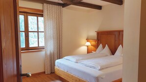 A bedroom with a wooden bed, a window with curtains, and a wooden floor.
