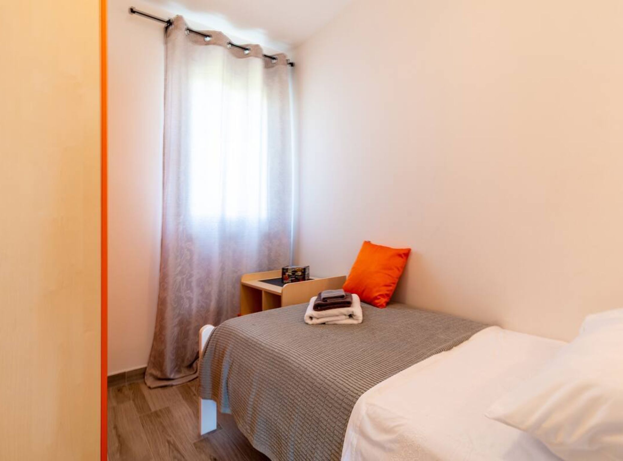 A small, neatly arranged bedroom with a bed, a bedside table, and a chair.