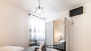 A modern bedroom with a bed, a bedside table, a mirror, and a TV mounted on the wall. - Holiday Home Sunny Side (Kastela)