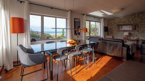A modern dining area with a glass table, grey chairs, and a view of the ocean. - La Entretenida -  View and Sound of the Sea, Next to the Beach. Pet-Friendly. (Doniños Ferrol)