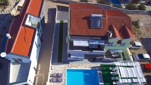 A modern residential building with a swimming pool, multiple balconies, and a covered outdoor area. - Villa Ava (Sibenik)