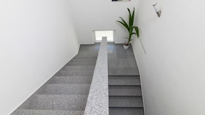 A staircase with a grey carpet leading to a landing area with a potted plant and a framed picture on the wall. - Villa Ava (Sibenik)