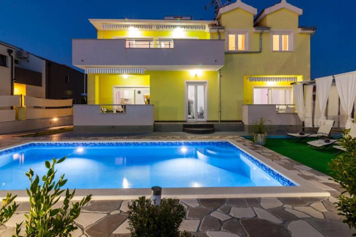 A two-story house with a swimming pool in the foreground.