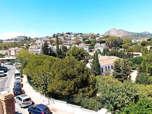 A residential area with a mountain in the background, a road with parked cars, and trees lining the street. - Flamencos del Cerrado G-2 Small studio with mountain views (Málaga)