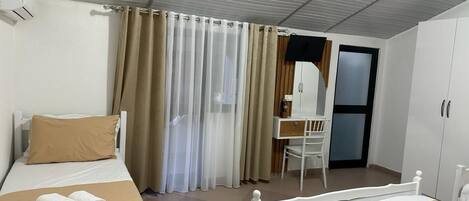 A hotel room with two beds, a desk, and a wardrobe.