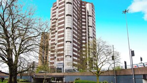 Ein Hochhaus mit moderner Architektur, das mehrere Balkone und einen markanten Eingang aufweist.
