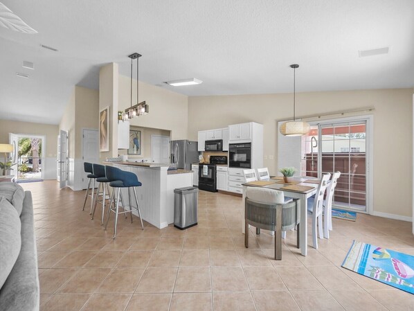 A spacious kitchen with white cabinets, a central island, and a dining area with a table and chairs.
