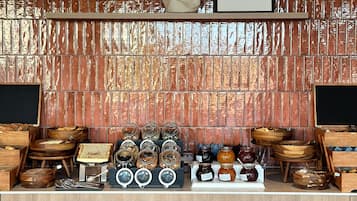 A kitchen area with a brick backsplash, wooden shelves, and various food items displayed.