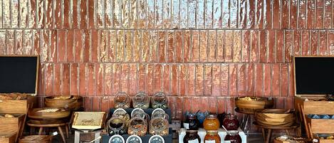 A kitchen area with a brick backsplash, wooden shelves, and various food items displayed.