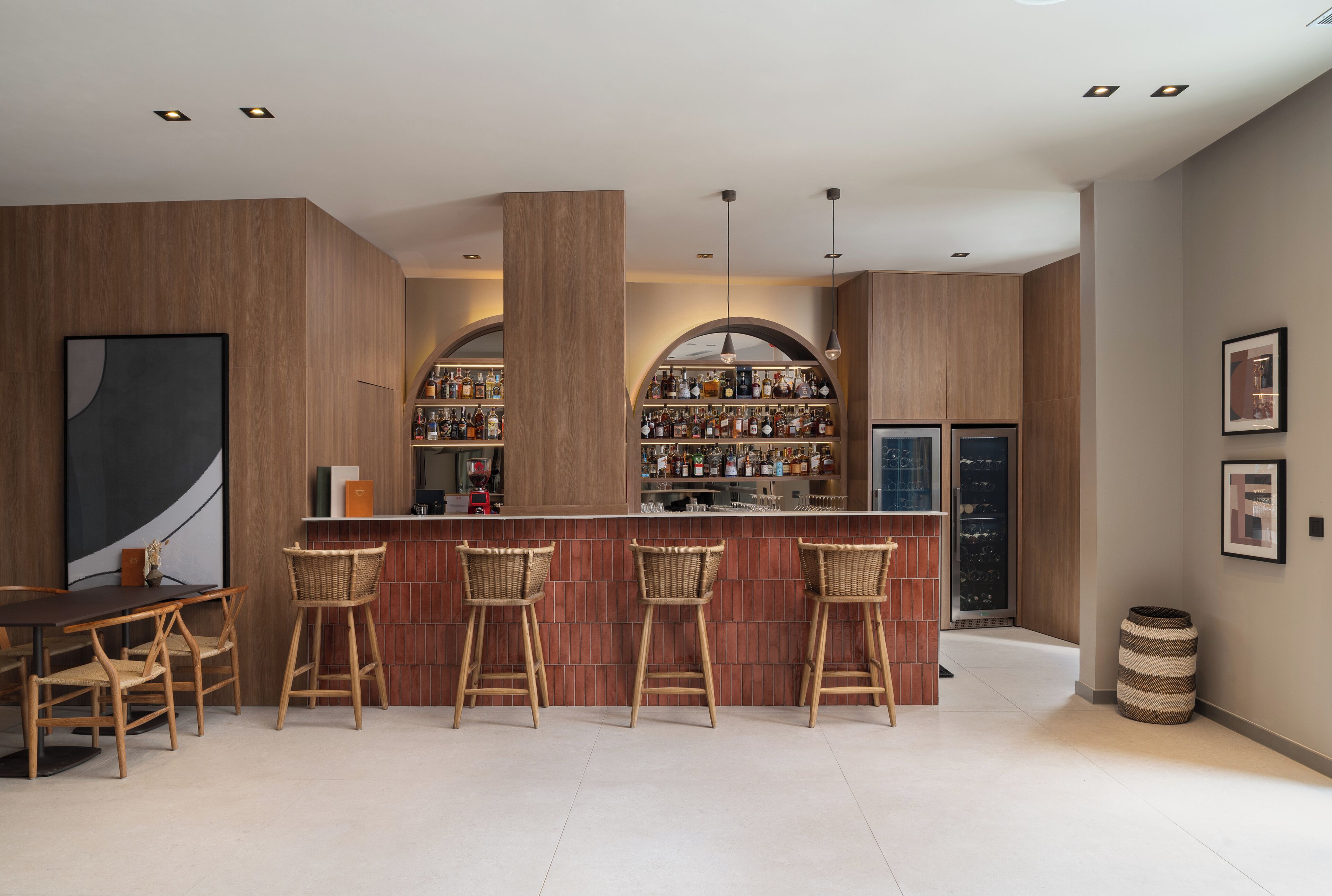 Una cocina moderna con barra, que incluye armarios de madera, una isla grande con taburetes y una estantería para vinos.