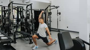 Une salle de sport équipée de matériel de musculation, notamment un support à squats et un banc.