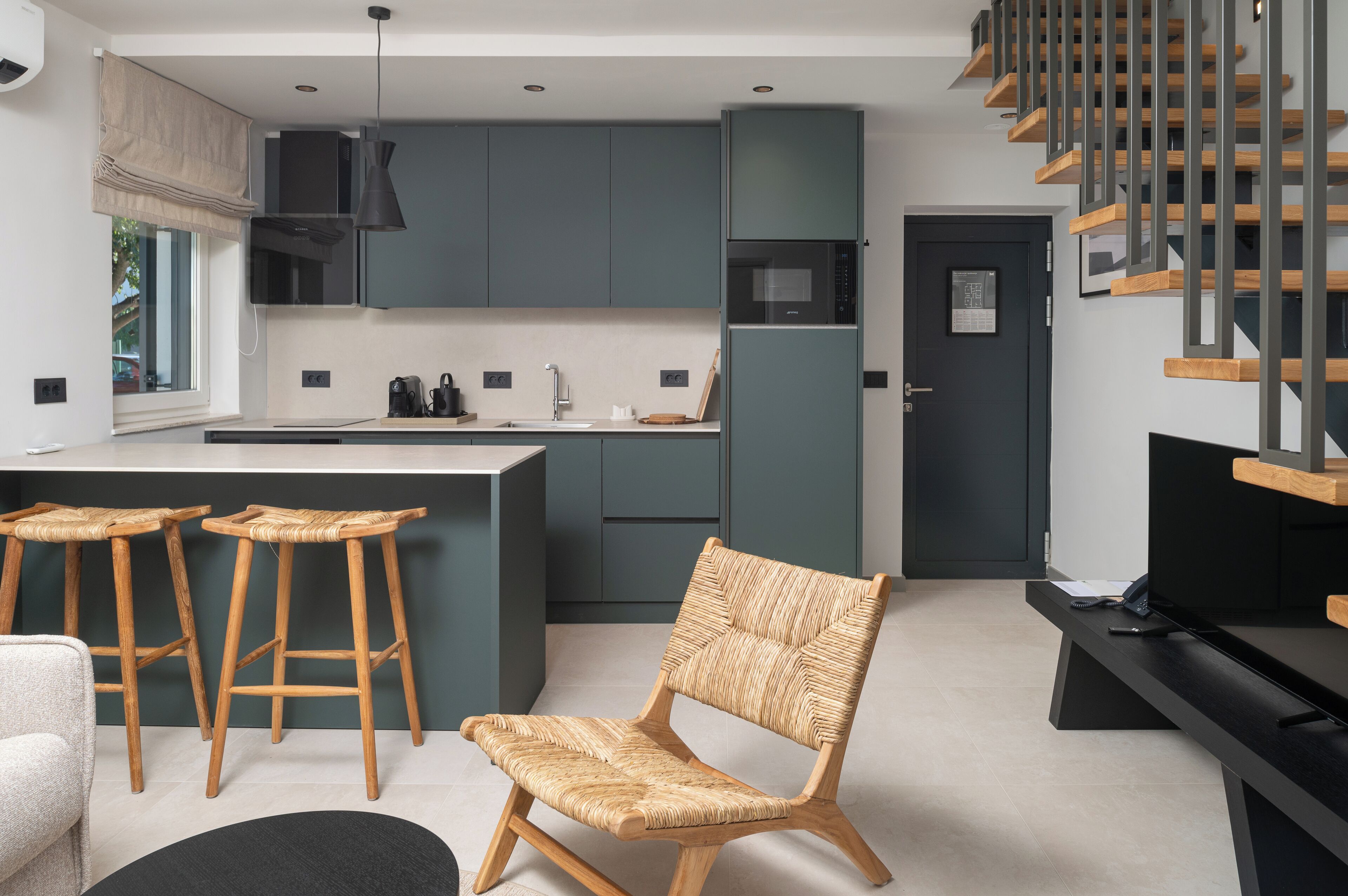 A modern kitchen with dark cabinets, a central island, and a wooden chair.