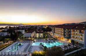 A resort with a large swimming pool, multiple buildings, and a view of the sunset over the water. - Molum Hotel & Residences (Sveti Filip i Jakov)