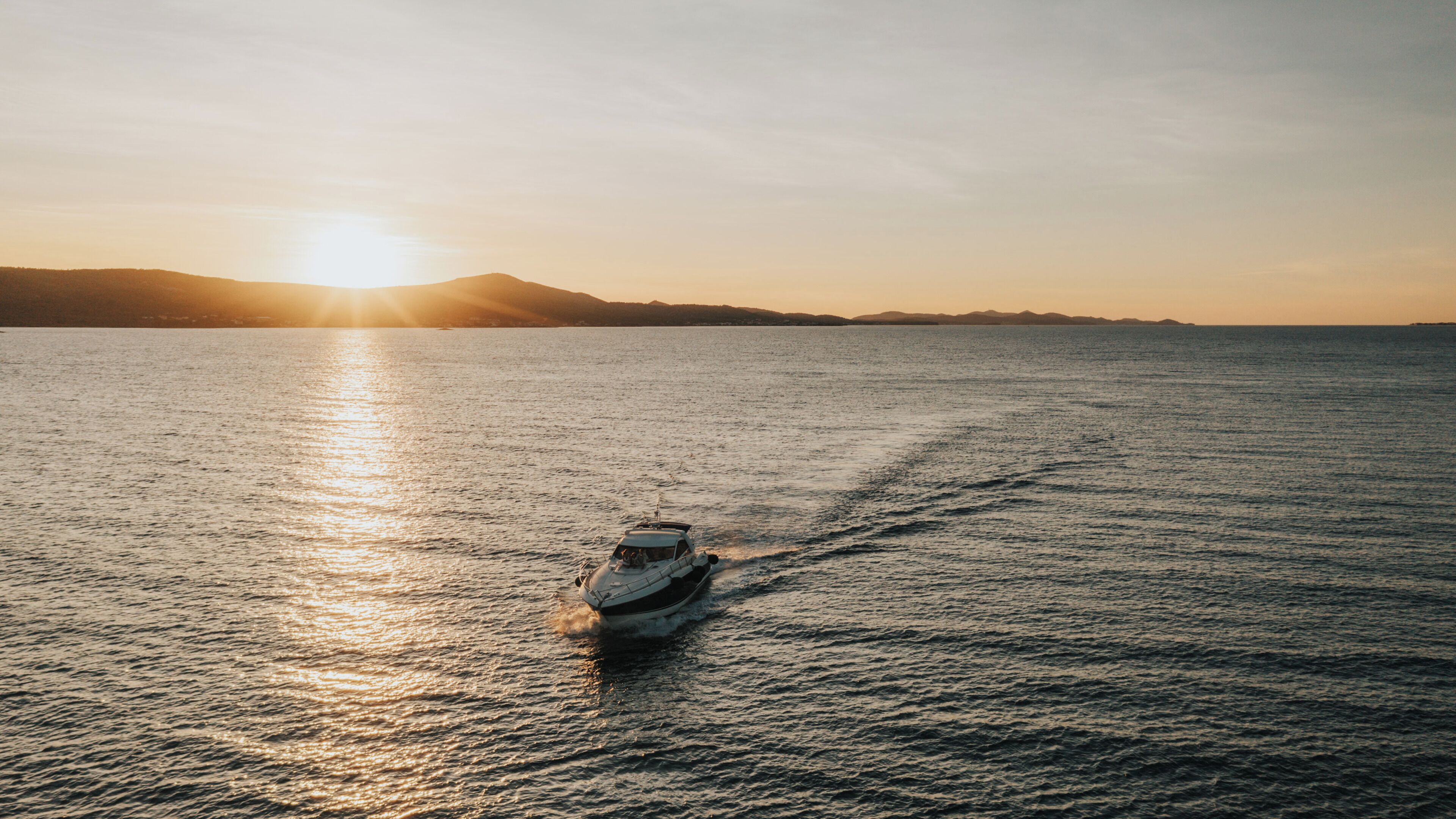 A boat on calm water with a sunset in the background.