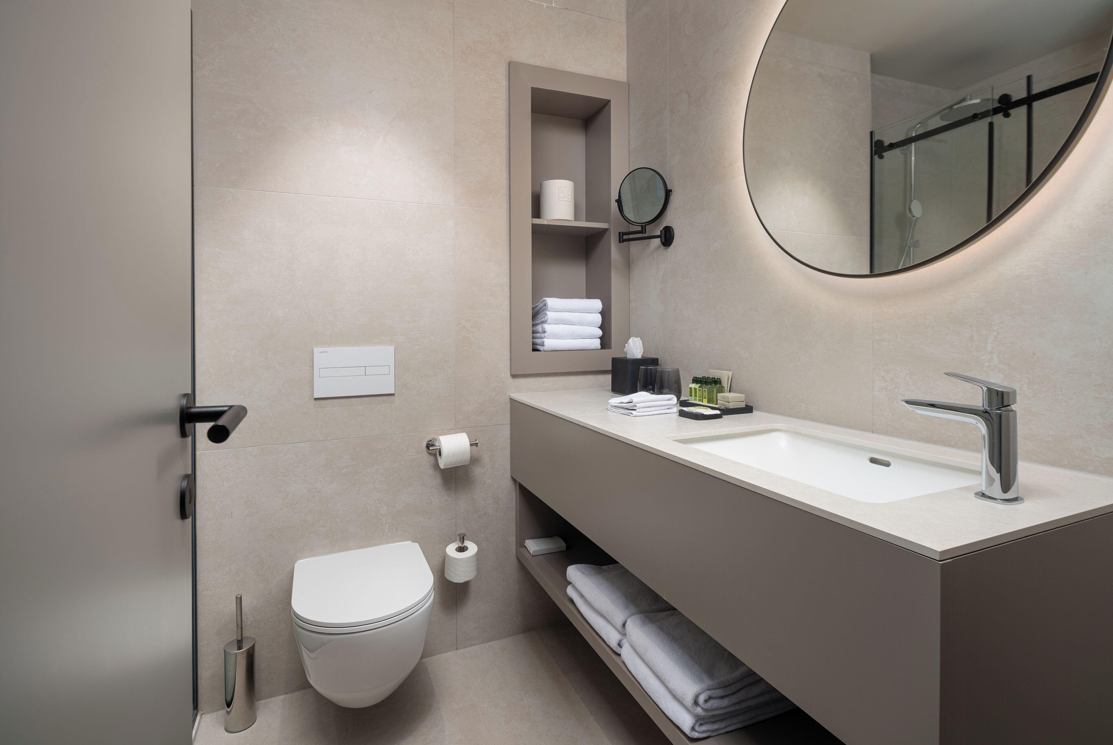 A modern bathroom with a toilet, sink, and mirror.