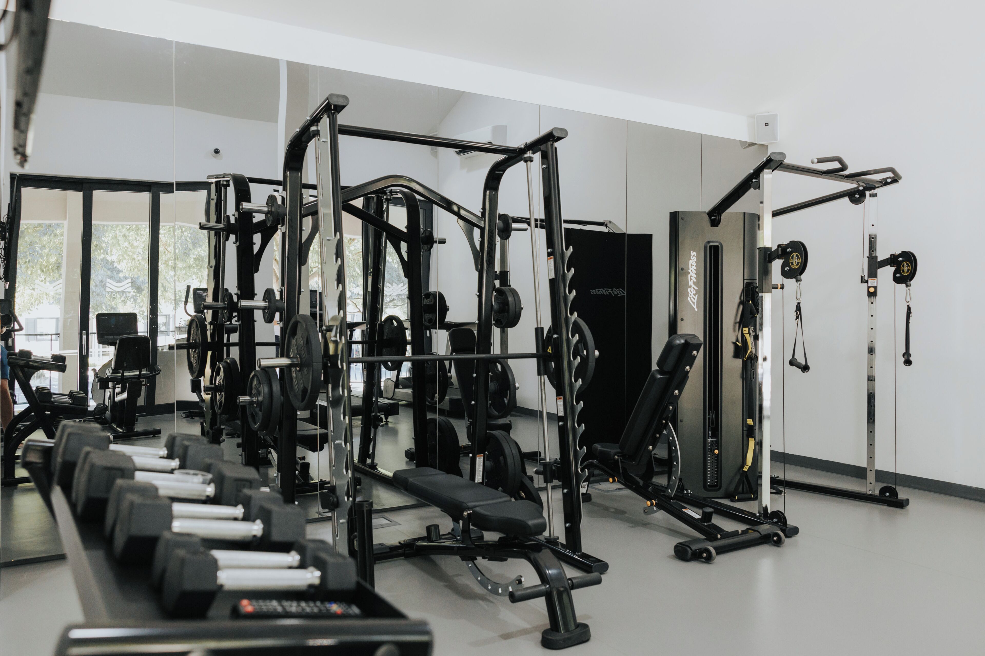Une salle de sport équipée de divers appareils d’entraînement, notamment des haltères, des bancs et des machines de musculation.