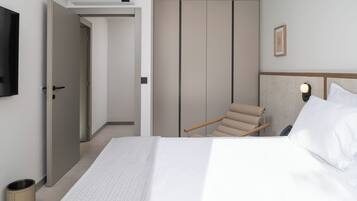 A hotel room with a bed, a chair, a wardrobe, and a TV on the wall.