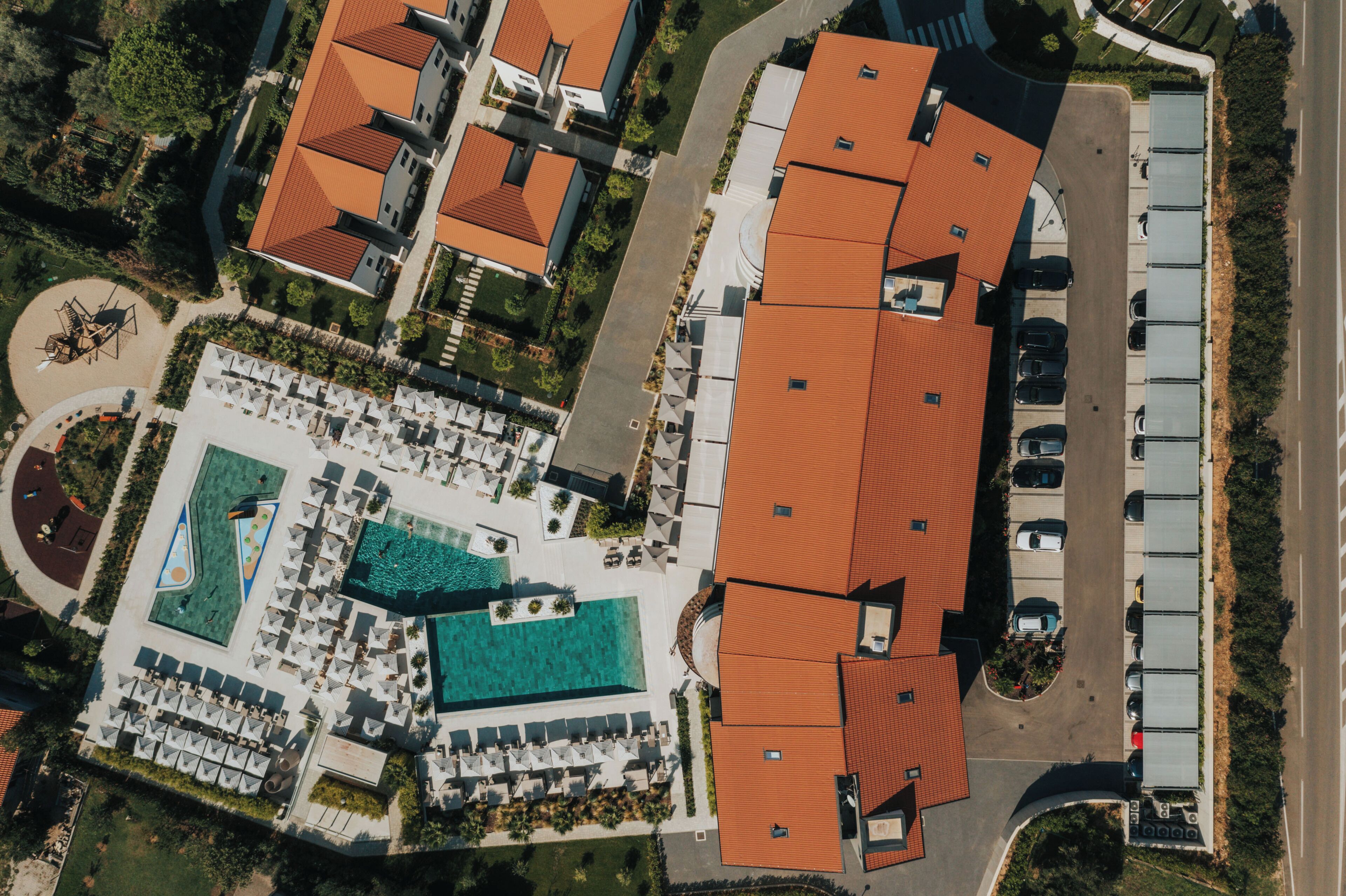 Luchtbeeld van een resort met meerdere gebouwen, een zwembad en een parkeerplaats.