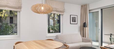 Een moderne woonkamer met een ronde houten tafel, bijpassende stoelen, een bank en een kleine zwarte tafel.