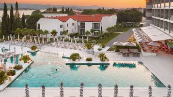 A resort with a swimming pool, lounge chairs, and a view of the surrounding landscape.