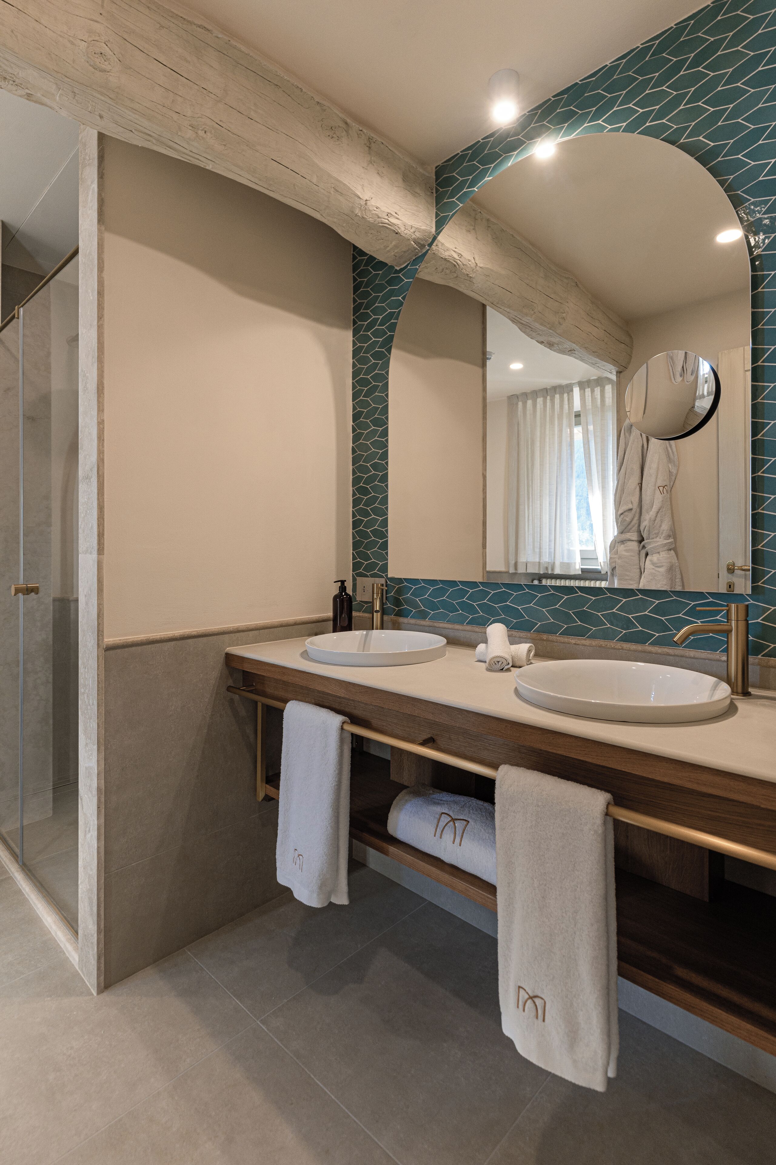 A modern bathroom with two sinks, a large mirror, and a shower area.