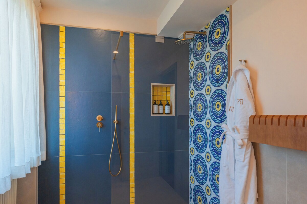 Un baño moderno con ducha, un perchero y un estante pequeño con artículos de tocador.