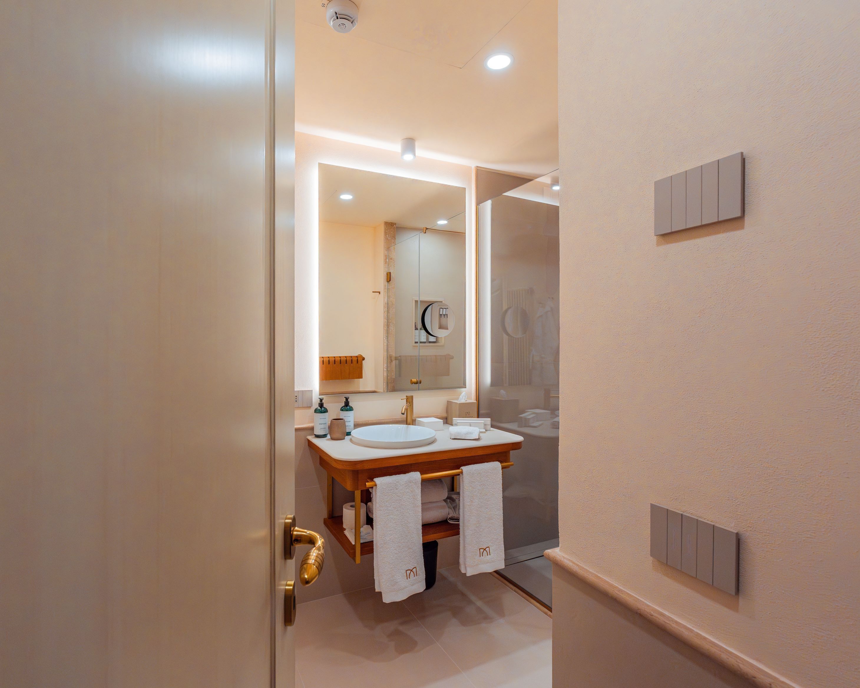Un bagno moderno con lavabo doppio, un ampio specchio e cabina doccia in vetro.