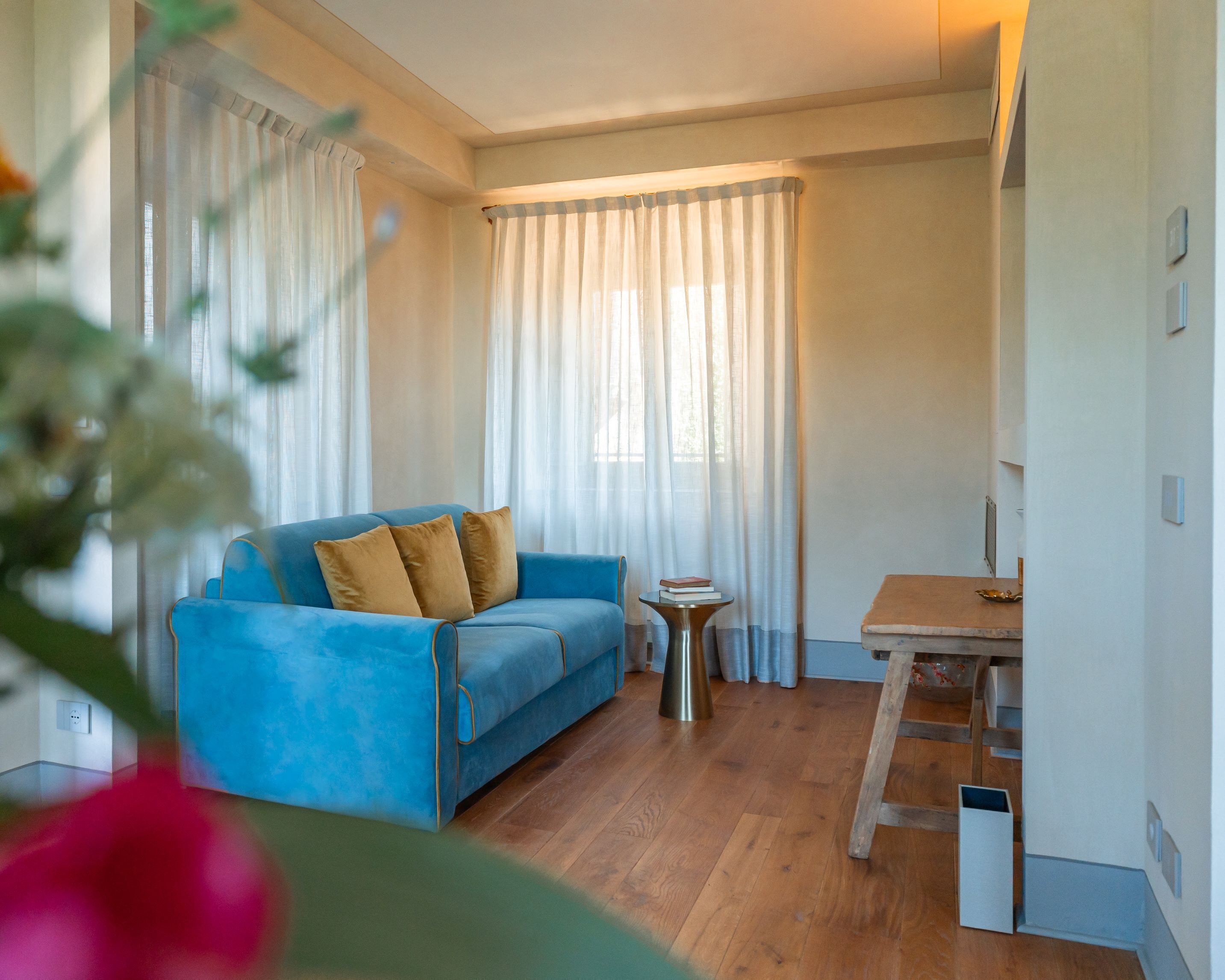 A room with a blue sofa, a small table, and a ladder against the wall.