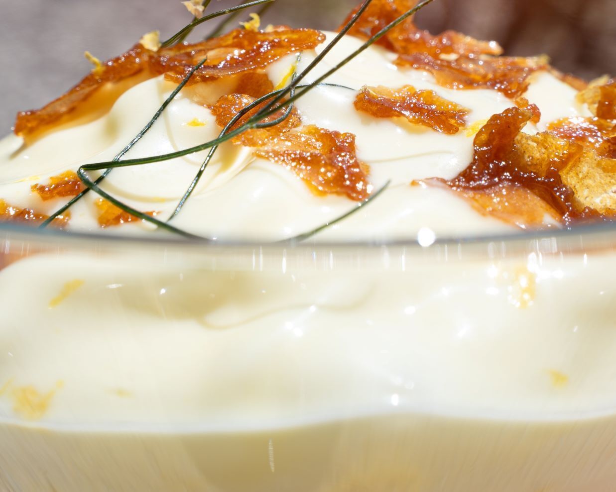 A bowl of creamy soup garnished with bacon and herbs.