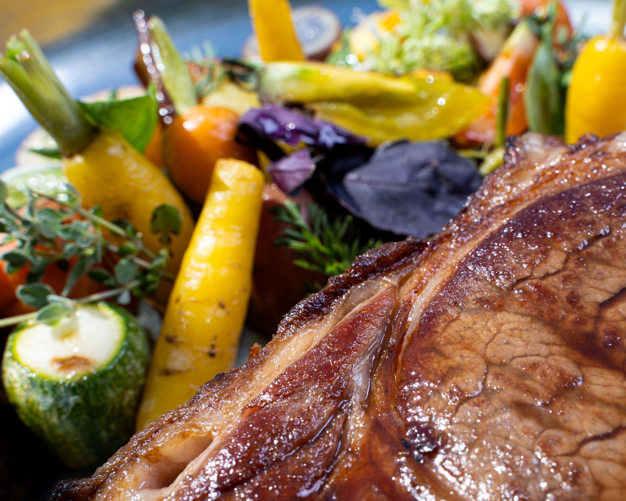 A close-up of a cooked steak with vegetables.