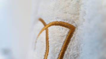 Nahaufnahme einer weißen, strukturierten Oberfläche mit goldener Stickerei.