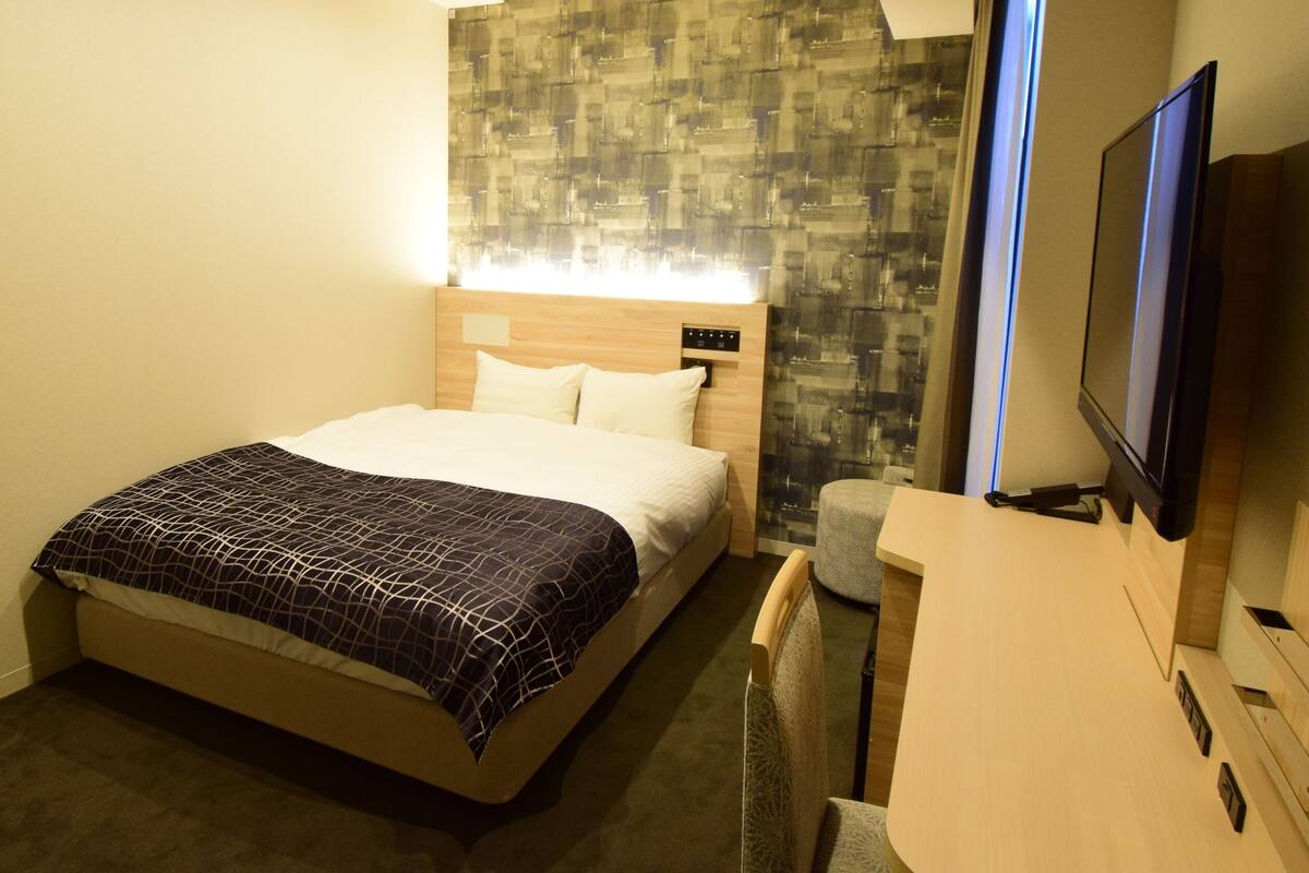 Een hotelkamer met een bed, een televisie, een bureau en een wand met een structuur.