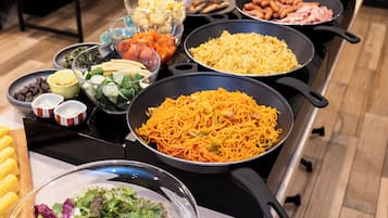 Un bufet amb diversos plats, com ara pasta, amanides i altres aliments preparats.