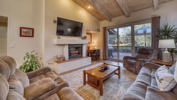 A cozy living room with a fireplace, comfortable seating, a flat-screen TV, and a view of the outdoors. - Sedona Bliss at Canyon Mesa Country Club (Sedona)