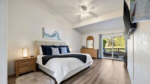 A bedroom with a large bed, a nightstand, a dresser, a ceiling fan, and a view of the outdoors through a sliding glass door. - Sedona Bliss at Canyon Mesa Country Club (Sedona)
