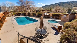 A pool area with two pools, lounge chairs, and a table with an umbrella. - Sedona Bliss at Canyon Mesa Country Club (Sedona)