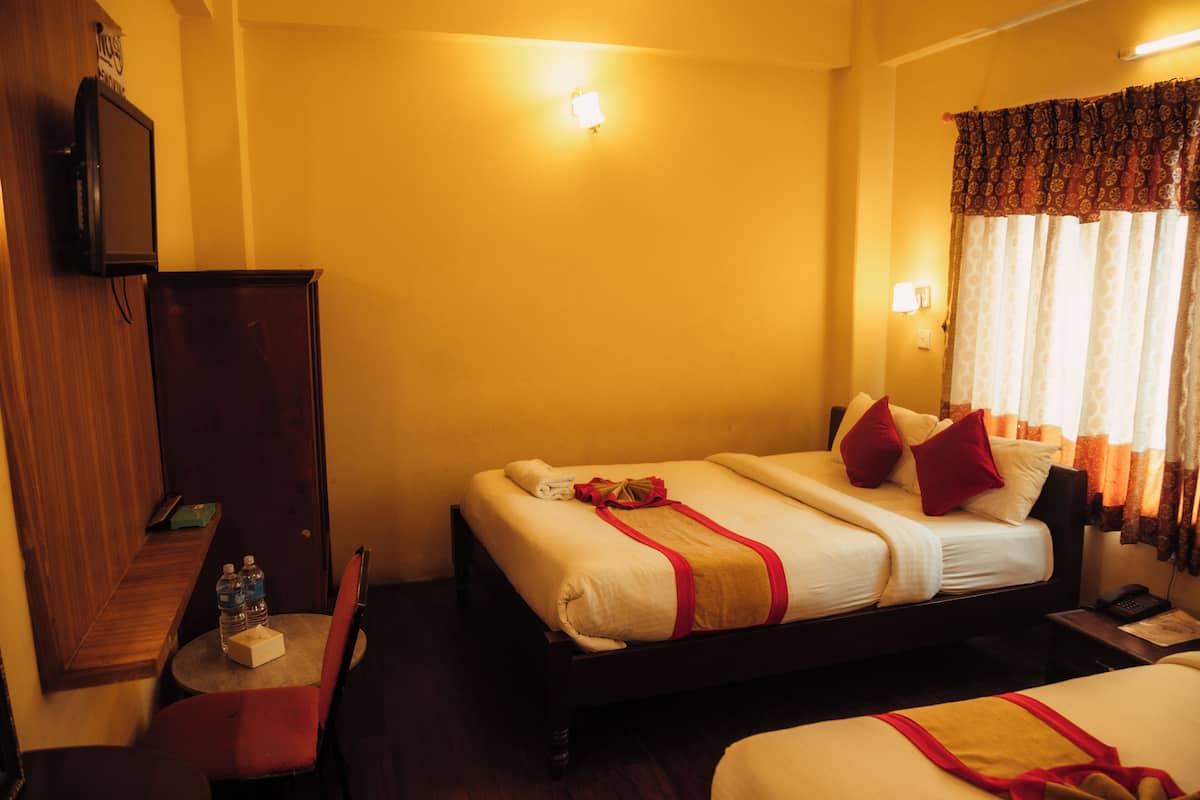 A hotel room with a bed, bedside table, and a television on a stand.
