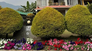 A multi-story hotel named 'Gantaby Inn' with a modern architectural design, featuring balconies and a well-maintained garden with colorful flowers. - Hotel Gantabya Inn (Pokhara)