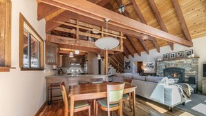 Een ruime woonkamer met een houten eettafel, stoelen, een bank en een open haard.