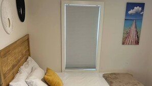 A bedroom with a bed, a window with blinds, a ceiling fan, and wall decorations.