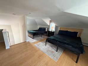 A room with two beds, a wooden floor, a white ceiling, and a window with curtains. - This house is a 1 bedroom(s), 1 bathrooms, located in Warwick, RI. (Warwick)