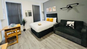 Ein modernes Hotelzimmer mit einem Bett, einer Couch, einem Schreibtisch und einem Spiegel.