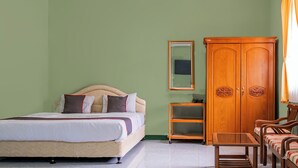 A bedroom with a bed, a wooden wardrobe, a small table, and two chairs. - Capital O 93949 Hotel Popuci By Pupa Hospitality (Cilimus)