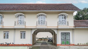 A two-story building with a tiled roof, arched windows, and a central entrance. - Capital O 93949 Hotel Popuci By Pupa Hospitality (Cilimus)