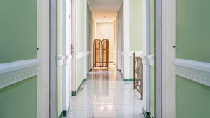 A hallway with a polished floor, white trim, and green walls. - Capital O 93949 Hotel Popuci By Pupa Hospitality (Cilimus)